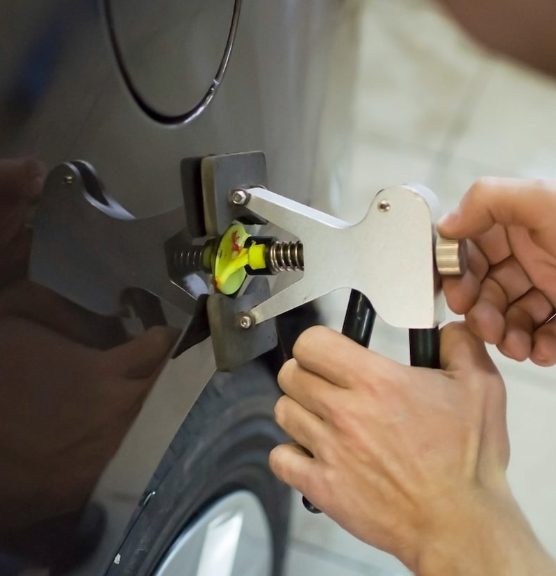 Technician performing dent removal on a vehicle.