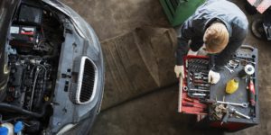 Top view of a mechanic repairing a car hood in a service center.